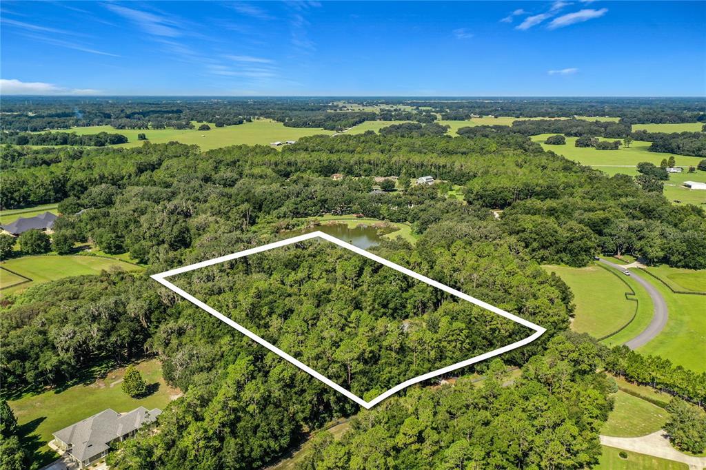 An aerial view shows a rectangular plot of land outlined in white amidst wooded terrain — 10620 NE 104TH CIRCLE, OXFORD, FL
