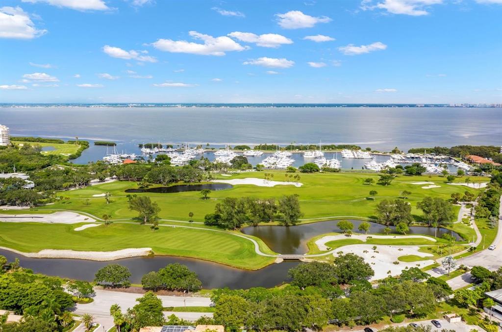 An aerial view of a golf course, a marina with many boats, and a large bay — 2600 HARBOURSIDE DRIVE UNIT R-02, LONGBOAT KEY, FL