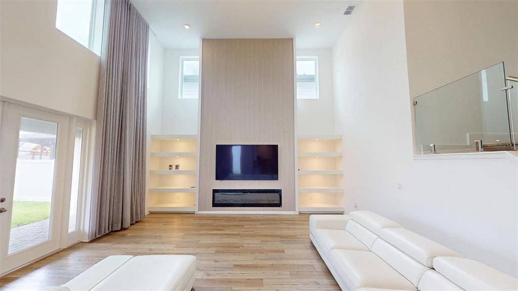 A living room features a tall fireplace wall with built-in shelves and light wood flooring — 17242 LAKE STAR ROAD, WINTER GARDEN, FL
