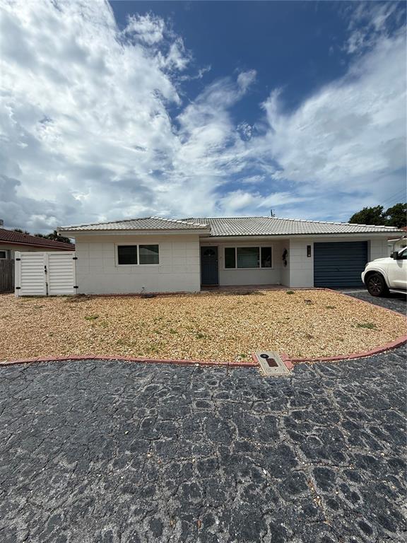 A single-story house with a white exterior, a gravel front yard, and a dark garage door — 52 45TH AVENUE, ST PETE BEACH, FL