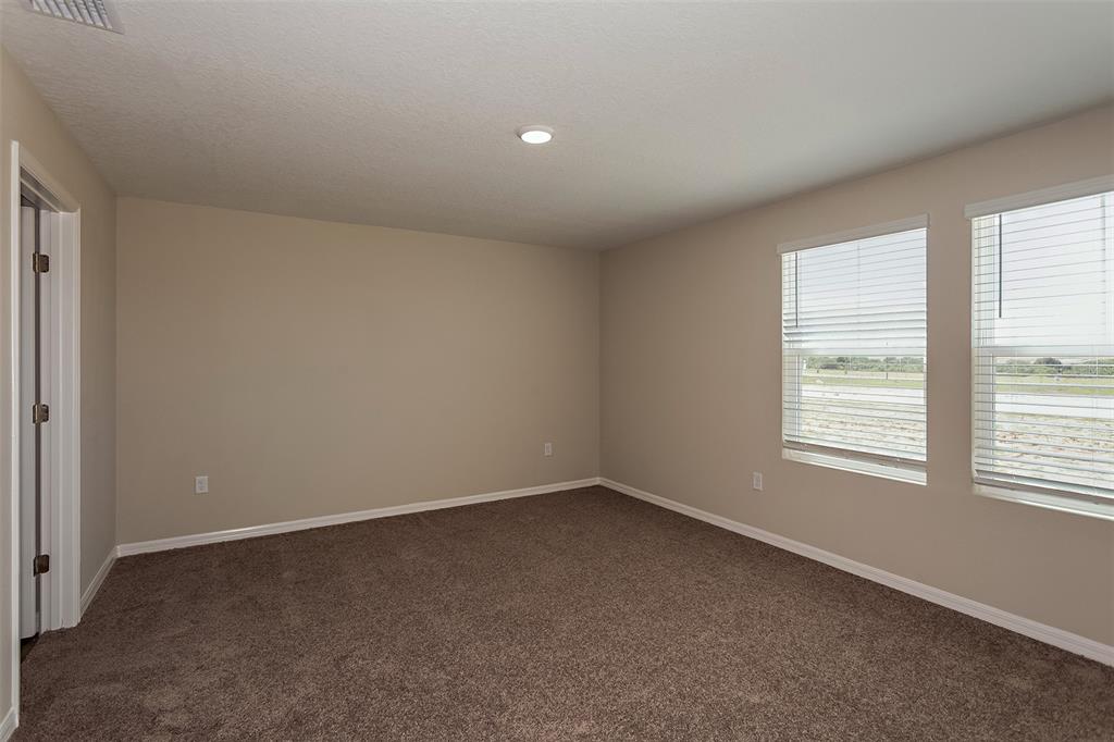 An empty bedroom features beige walls, brown carpet, and two windows with white blinds — 15257 MAUDE LANDING LOOP, WIMAUMA, FL