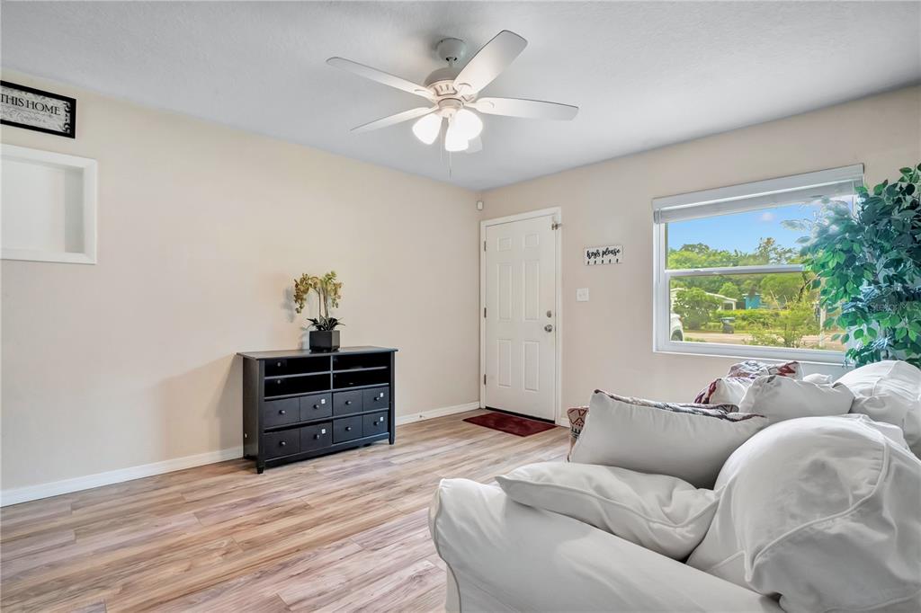 A living room features light walls, wood-look flooring, a ceiling fan, and a white door — 4901 BRISTOL COURT, ORLANDO, FL