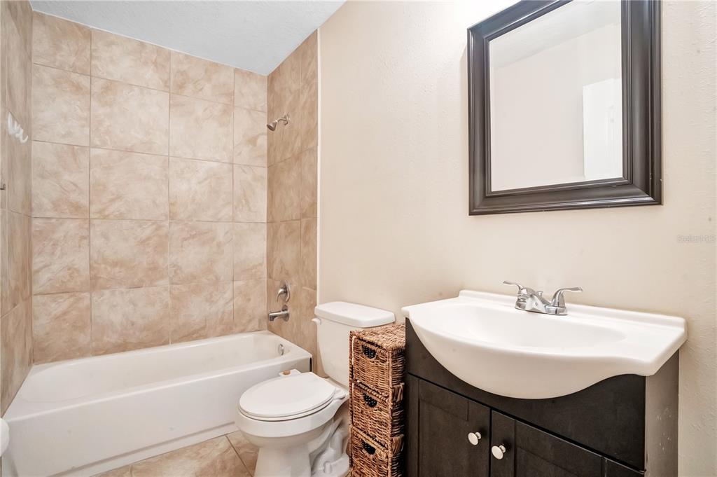 A bathroom features a tiled shower-tub combo, a white toilet, and a dark wood vanity — 4901 BRISTOL COURT, ORLANDO, FL