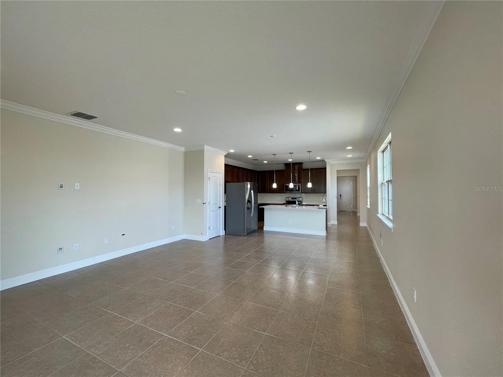 An open-concept living area features tile flooring, a kitchen with dark cabinets, and an island — 3430 SAGEBRUSH STREET, HARMONY, FL
