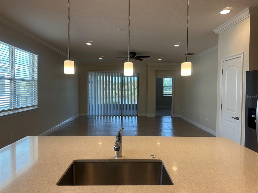 A kitchen island with a stainless steel sink overlooks an open-concept living area — 3430 SAGEBRUSH STREET, HARMONY, FL
