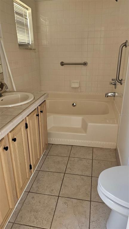 A bathroom features a tiled tub-shower combination, a wooden vanity, and a white toilet — 13109 ELGAR PLACE, RIVERVIEW, FL