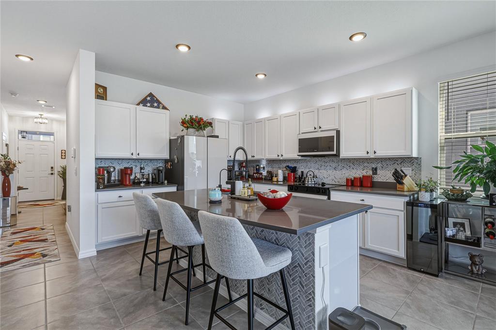 A kitchen features white cabinets, a large gray island with seating, and stainless steel appliances — 388 MANGROVE SHADE CIRCLE, APOLLO BEACH, FL