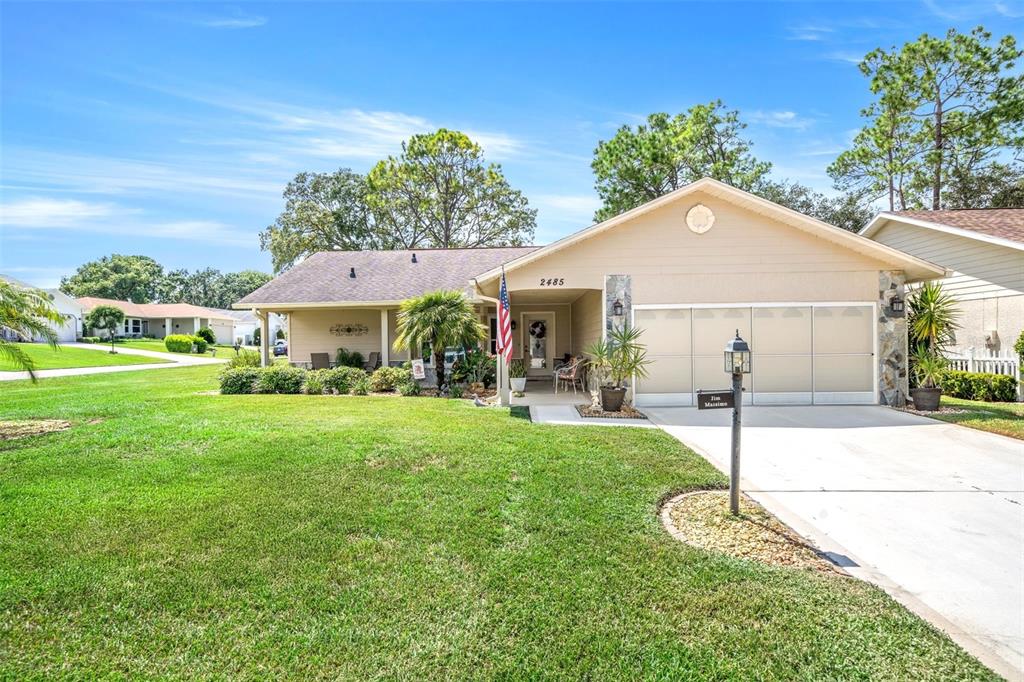 A single-story house with a tan exterior, a two-car garage, and a front lawn — 2485 BROOKLAWN STREET, SPRING HILL, FL