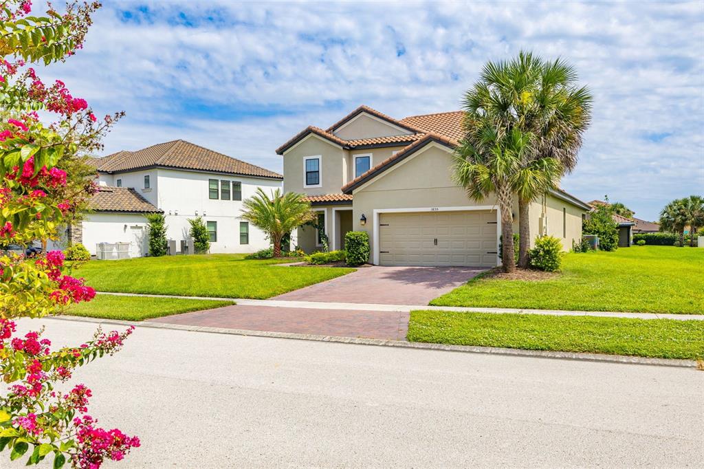 A two-story suburban house with a tan stucco exterior, a tiled roof, and a paved driveway — 3855 BOWFIN TRAIL, KISSIMMEE, FL
