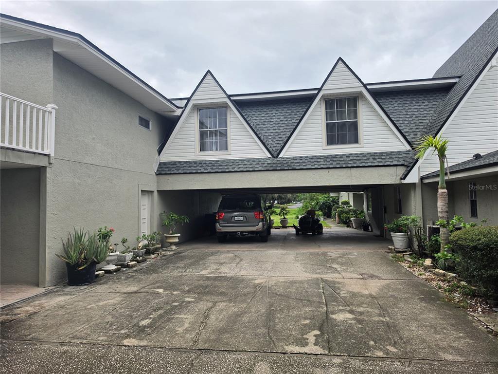A concrete driveway leads to a covered parking area beneath a two-story residential building — 201 LAKE BONNY DRIVE E, LAKELAND, FL