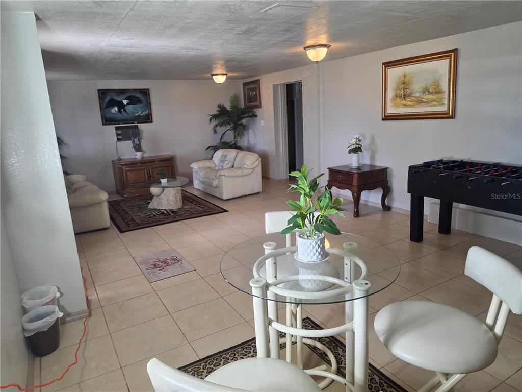 A living room and dining area with tile floors, white furniture, and a foosball table — 201 LAKE BONNY DRIVE E, LAKELAND, FL