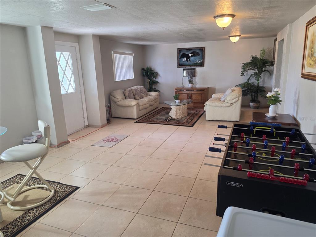 A living room with tile floors, two sofas, a foosball table, and a white door — 201 LAKE BONNY DRIVE E, LAKELAND, FL