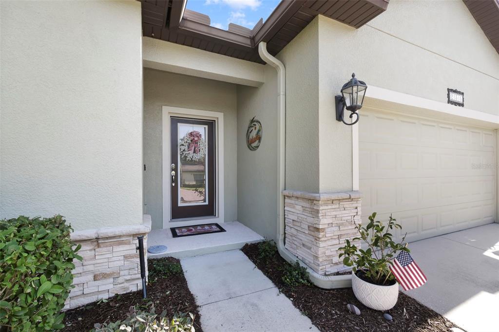 The exterior front entrance features a brown door, stone accents, and a garage — 21315 SORRAIA COVE, MOUNT DORA, FL