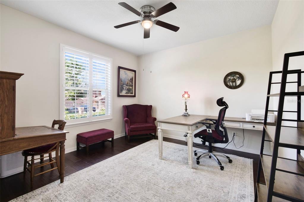 A home office with dark wood floors, a desk, an armchair, and a ceiling fan — 21315 SORRAIA COVE, MOUNT DORA, FL
