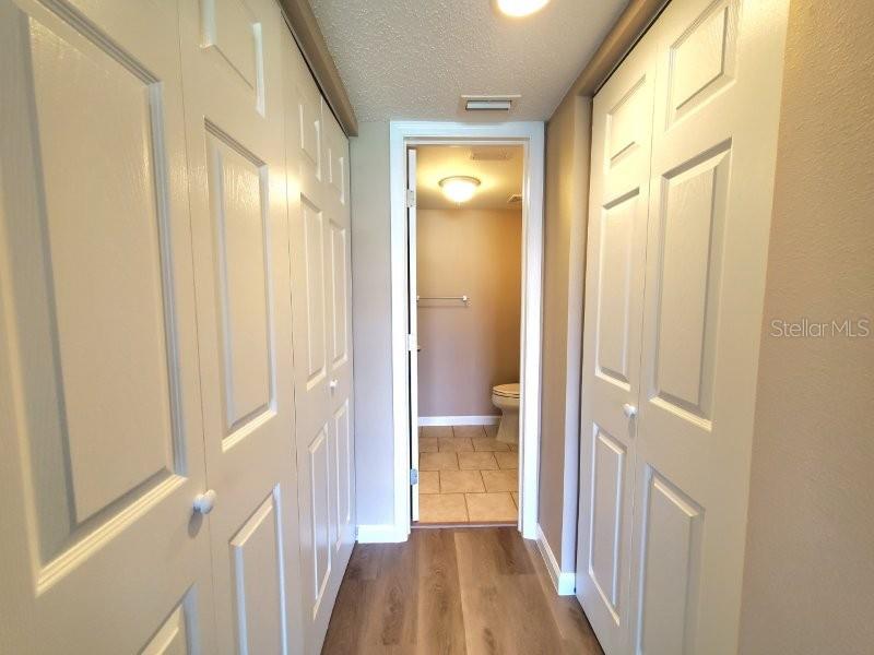 A hallway with white bi-fold closet doors leads to a bathroom with tiled flooring — 1080 BAL HARBOR BOULEVARD UNIT 10A, PUNTA GORDA, FL