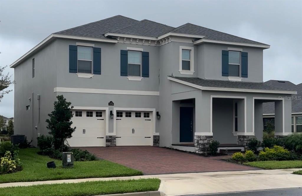 A two-story suburban house with a brick driveway, two-car garage, and a front lawn — 12728 CHARMED DRIVE, WINTER GARDEN, FL
