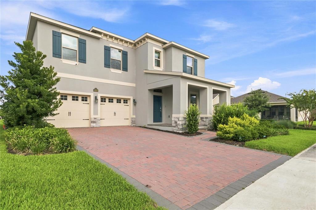 A two-story suburban house with a brick paver driveway, two-car garage, and blue shutters — 12728 CHARMED DRIVE, WINTER GARDEN, FL