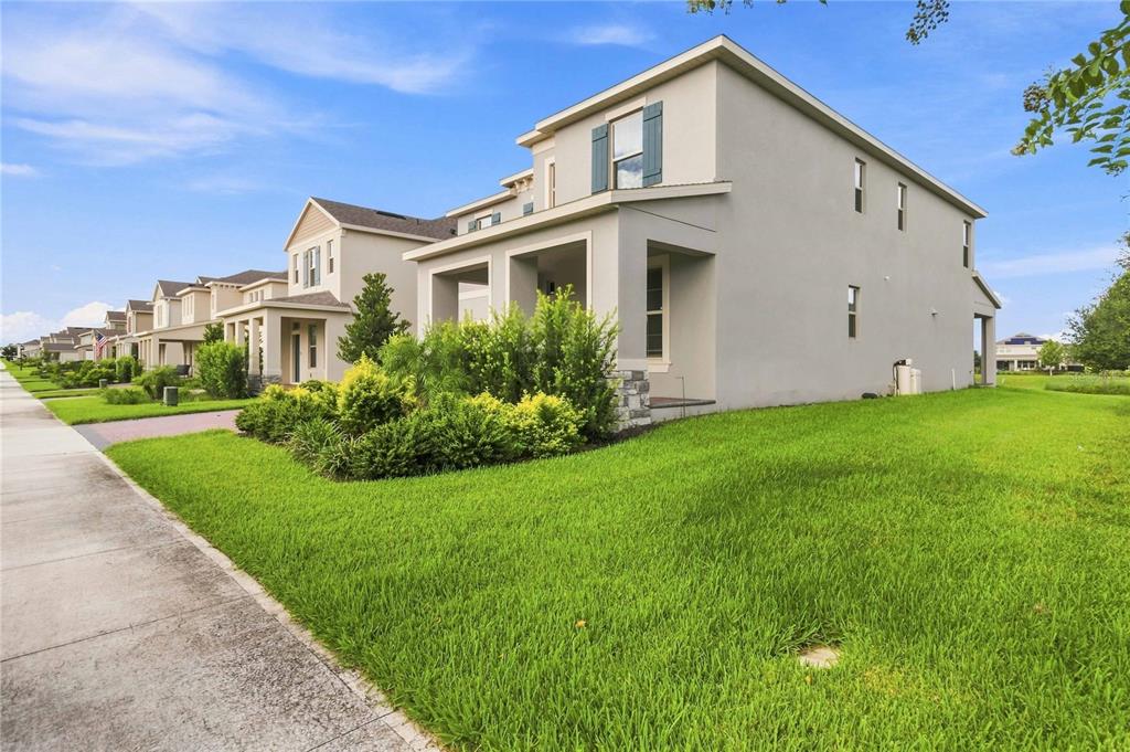 A two-story house with a light-colored stucco exterior and a green lawn — 12728 CHARMED DRIVE, WINTER GARDEN, FL