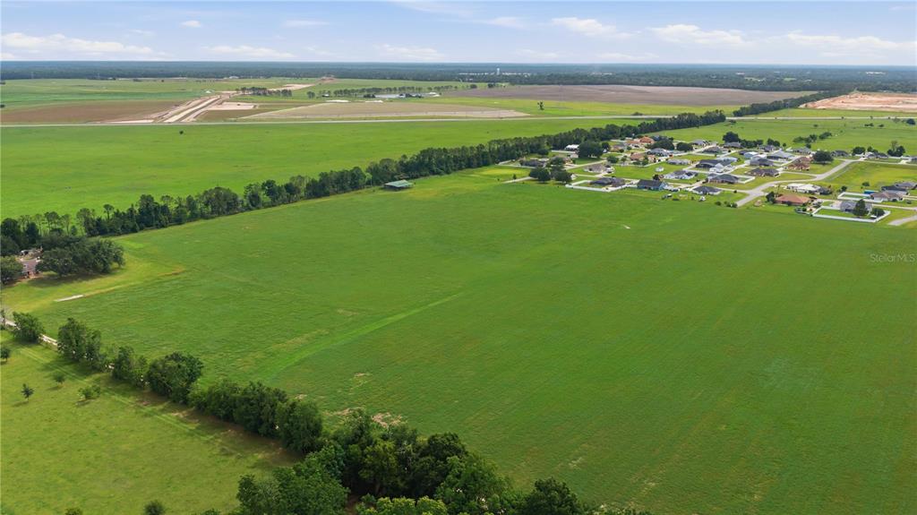 An aerial view shows a large, open green field adjacent to a residential neighborhood — 106TH PL, BELLEVIEW, FL