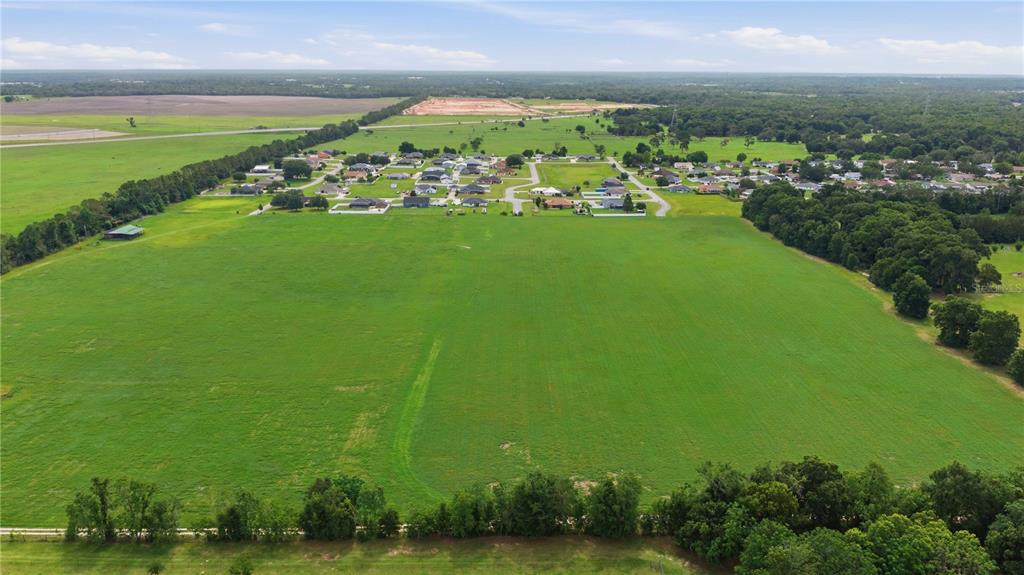 An aerial view shows a large, open green field adjacent to a residential neighborhood — 106TH PL, BELLEVIEW, FL
