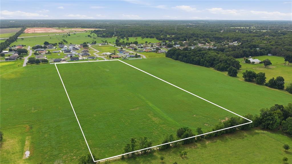 An aerial view shows a large, rectangular plot of open green land outlined in white — 106TH PL, BELLEVIEW, FL