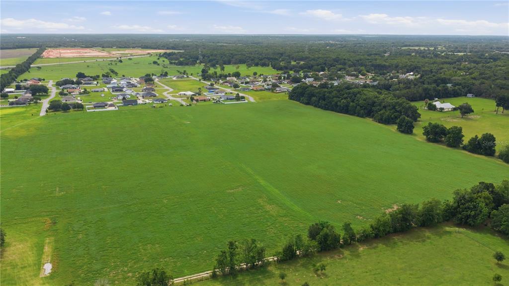 An aerial view shows a large, open green field adjacent to a residential neighborhood — 106TH PL, BELLEVIEW, FL