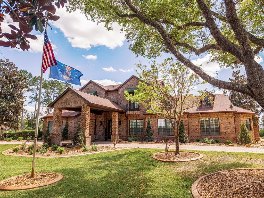An aerial view shows a large house with a pool, dock, and lawn near a lake — 6900 RANCHERO COURT, ST CLOUD, FL