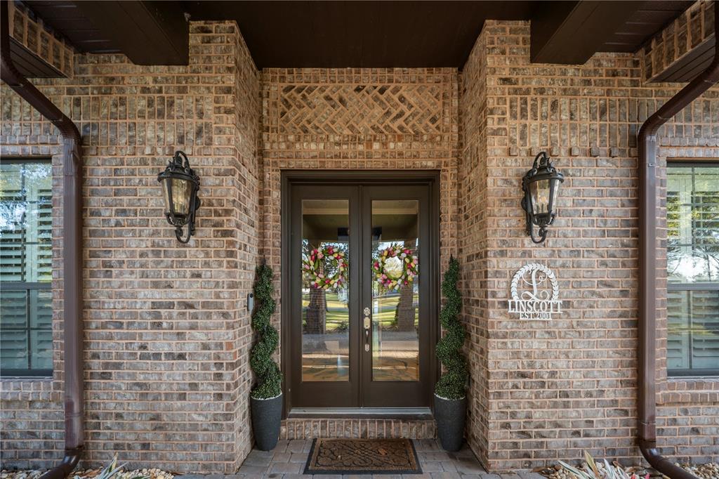 A brick house entrance features double glass doors, two lanterns, and topiary plants — 6900 RANCHERO COURT, ST CLOUD, FL