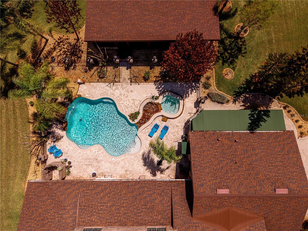 An aerial view shows a house with a swimming pool, hot tub, and patio area — 6900 RANCHERO COURT, ST CLOUD, FL