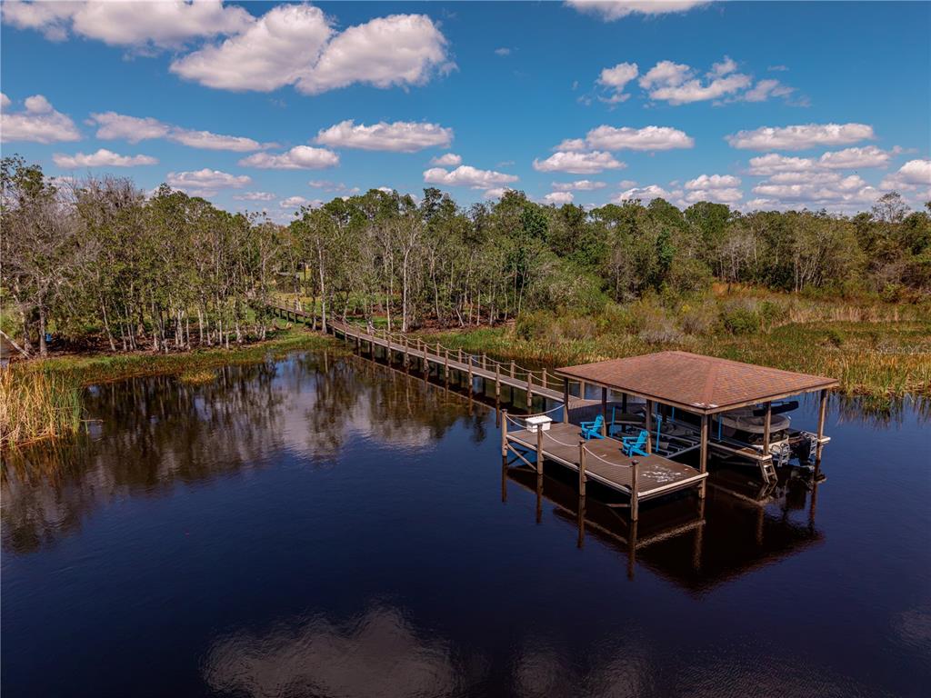 An aerial view of a long wooden dock leading to a covered boat slip — 6900 RANCHERO COURT, ST CLOUD, FL