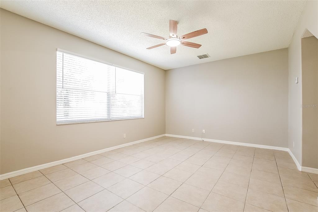A living room with beige tile floors, a ceiling fan, and an arched kitchen pass-through — 14401 KRISTENRIGHT LANE, ORLANDO, FL
