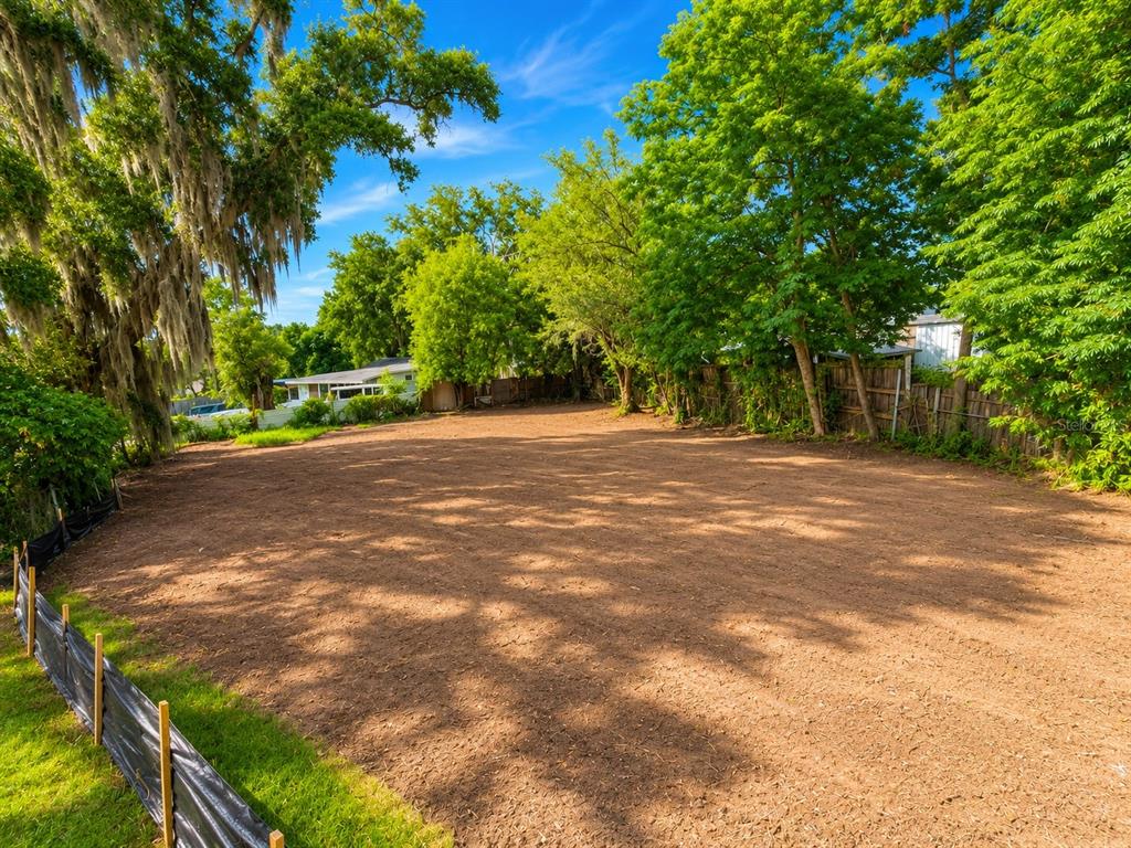 A cleared, vacant residential lot features bare soil surrounded by mature trees and a fence — 1185 APOPKA BOULEVARD, APOPKA, FL