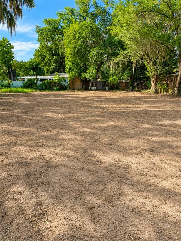 A large, cleared, sandy residential lot is surrounded by mature trees and a wooden fence — 1185 APOPKA BOULEVARD, APOPKA, FL