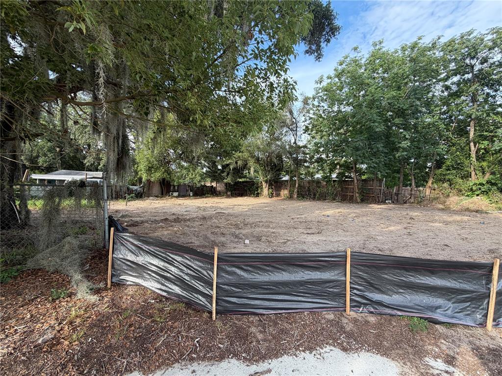 A vacant, cleared residential lot is enclosed by a black silt fence and mature trees — 1185 APOPKA BOULEVARD, APOPKA, FL