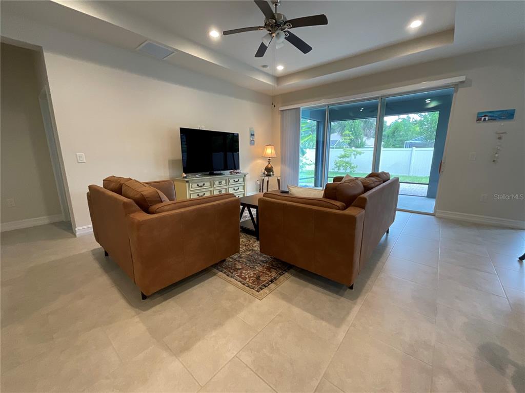 A living room features two brown sofas, a television on a console, and sliding glass doors — 4428 CONCHFISH LANE, OSPREY, FL
