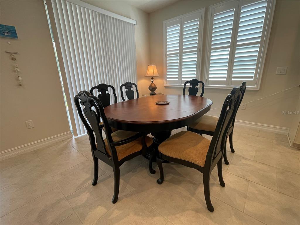 A dining room features a dark wood table with four chairs on a tiled floor — 4428 CONCHFISH LANE, OSPREY, FL