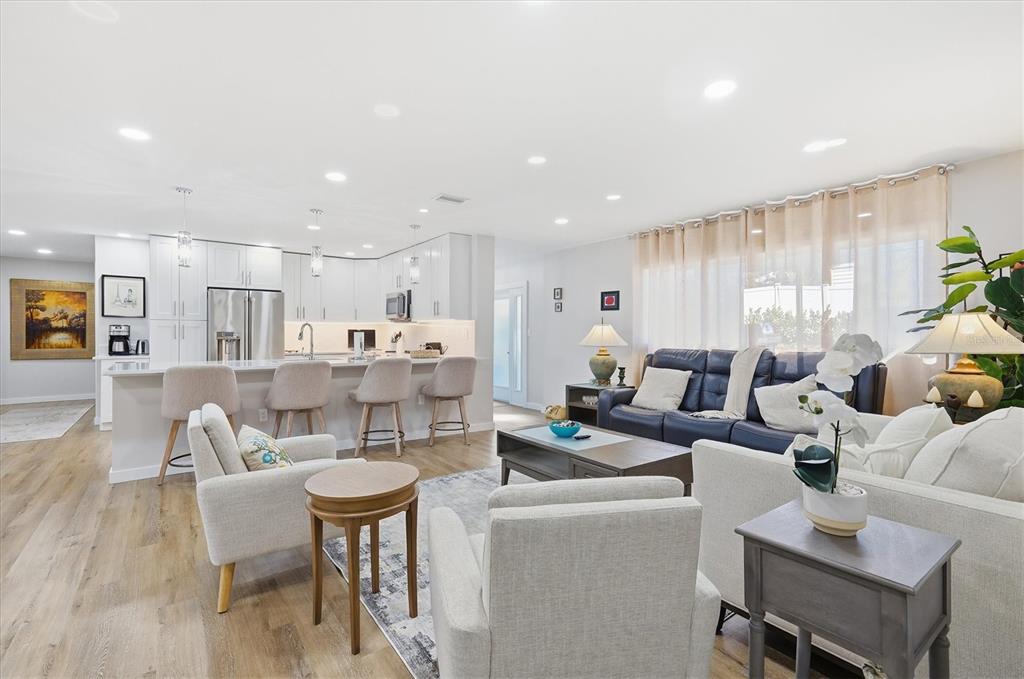 An open-concept living room and kitchen featuring light wood flooring and white cabinetry — 5247 CARMILFRA DRIVE, SARASOTA, FL