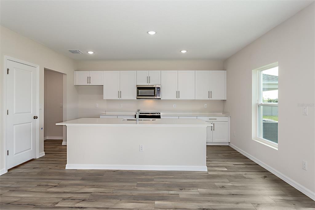 A kitchen with white cabinets, a central island, and wood-look flooring — 36715 THORNHEDGE DRIVE, ZEPHYRHILLS, FL