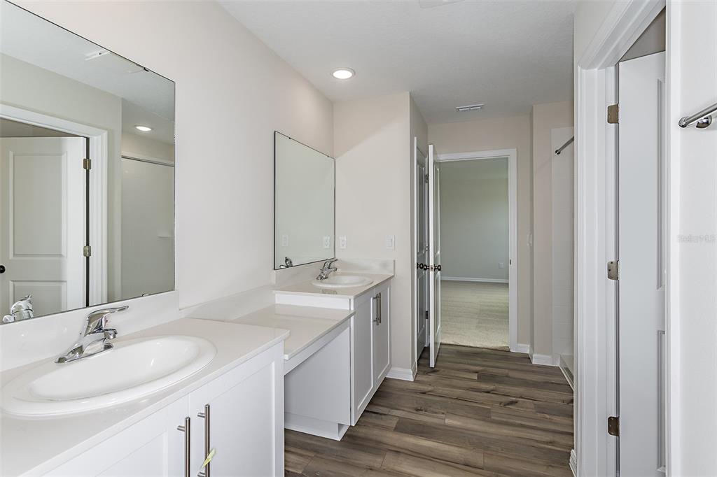 A bathroom features a double vanity with white cabinets, light countertops, and wood-look flooring — 36715 THORNHEDGE DRIVE, ZEPHYRHILLS, FL