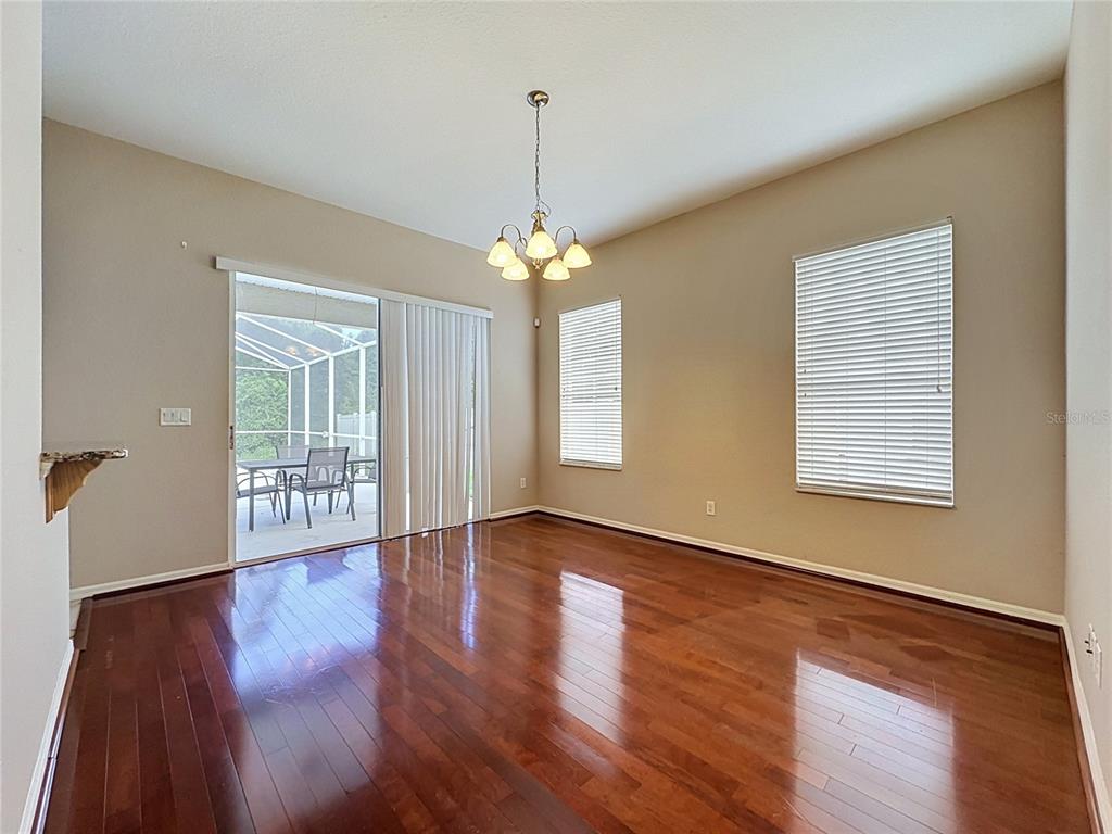 A dining room features hardwood floors, a chandelier, and a sliding glass door to a patio — 468 PINEWOOD DR, DAVENPORT, FL