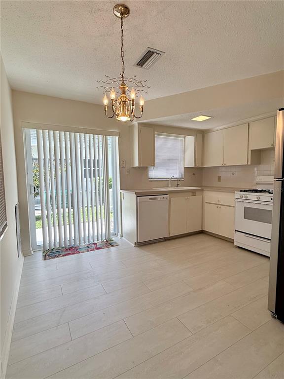 A kitchen with white cabinets, light tile flooring, and a sliding glass door to outside — 7847 39TH TERRACE N, ST PETERSBURG, FL