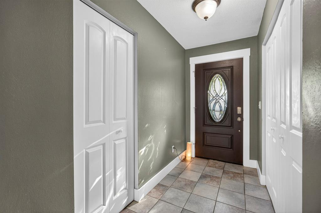 An entryway features tiled flooring, a dark brown front door with glass, and white closets — 2207 KARL STREET UNIT B, LEESBURG, FL
