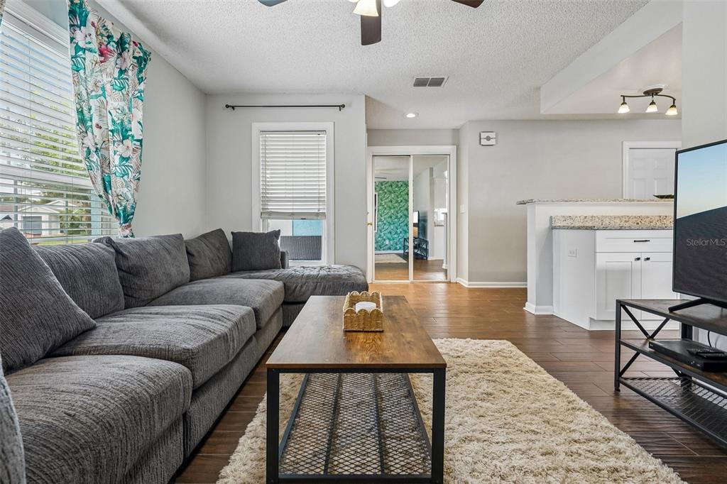 A living room features a gray sectional sofa, a wooden coffee table, and wood-look flooring — 4717 W PRESCOTT STREET, TAMPA, FL