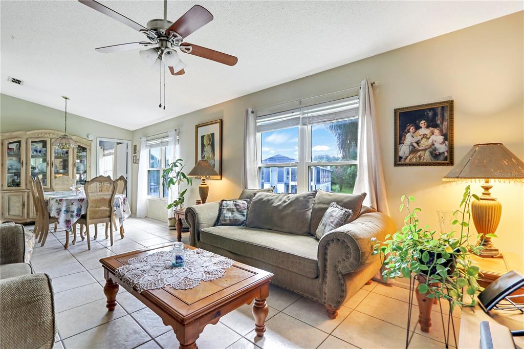 A living room with tile floors, a beige sofa, a wooden coffee table, and dining area — 2005 NORTHLAKE DRIVE, SANFORD, FL
