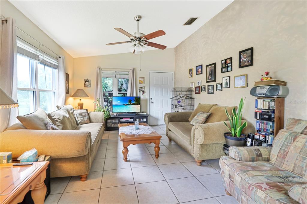 A living room features tile flooring, two beige sofas, a wooden coffee table, and a ceiling fan — 2005 NORTHLAKE DRIVE, SANFORD, FL