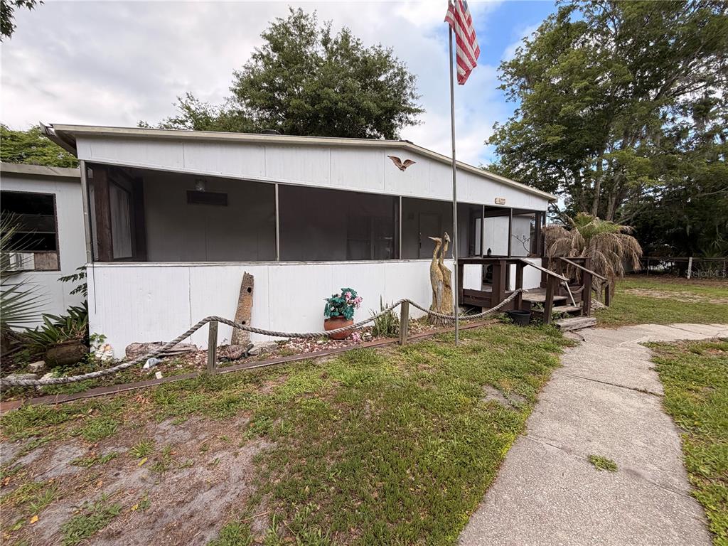 A single-story house with a screened-in porch, a flag pole, and a rope fence — 24021 ARMADILLO ROAD, ASTOR, FL