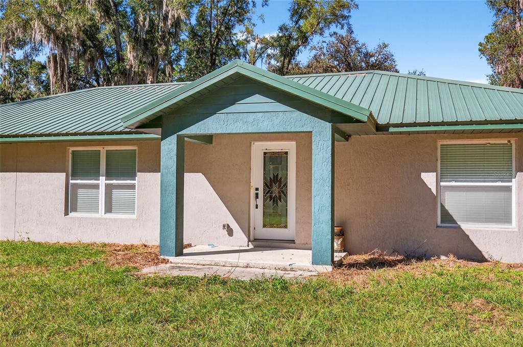 A single-story house with a green metal roof and a covered front entryway — 201 N WEST STREET, INTERLACHEN, FL