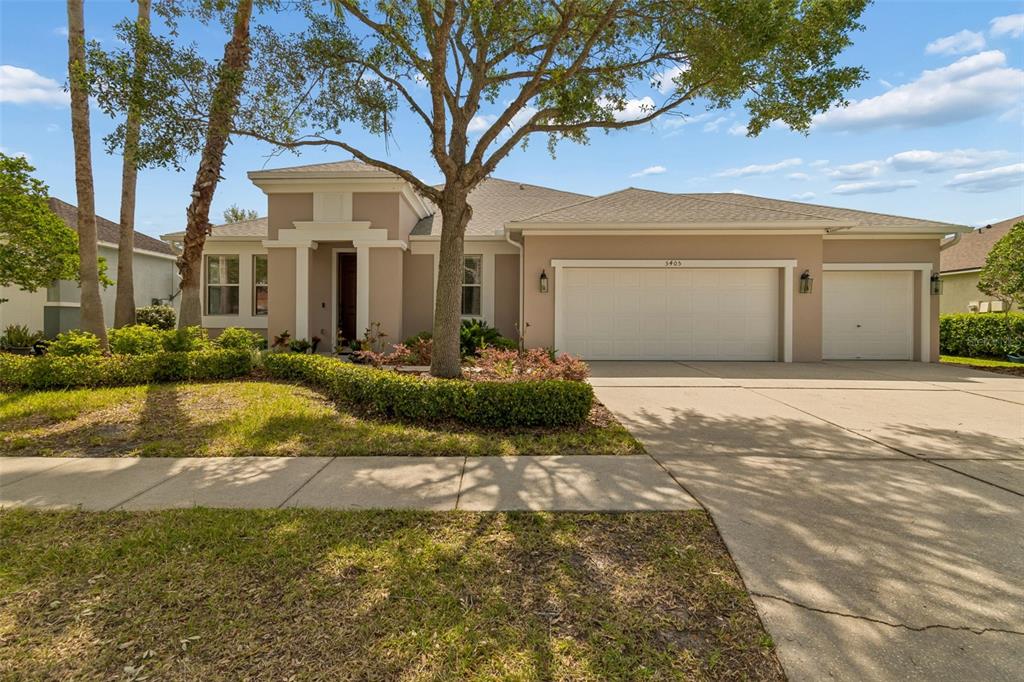 A single-story house with a beige stucco exterior, a three-car garage, and a landscaped yard — 5405 HAMMOCK VIEW LANE, APOLLO BEACH, FL