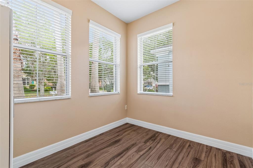 An empty room with tan walls, wood-look flooring, and three windows with white blinds — 5405 HAMMOCK VIEW LANE, APOLLO BEACH, FL
