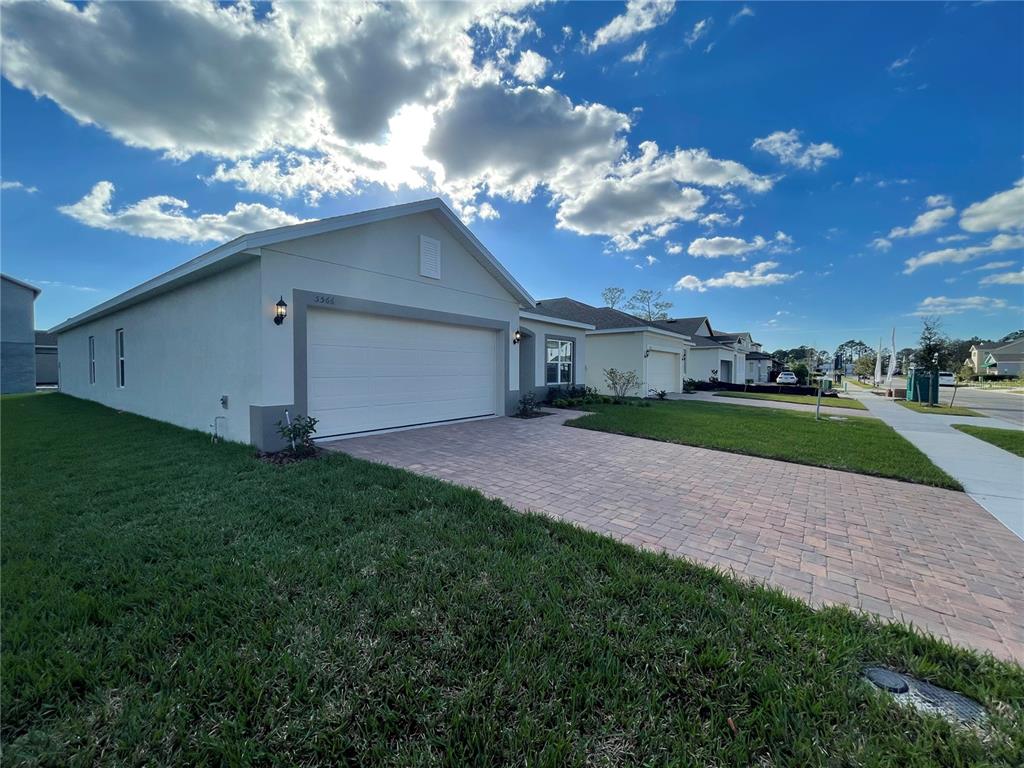 A single-story house with a white stucco exterior, a two-car garage, and a paved driveway — 5566 SABAL DRIVE, ST CLOUD, FL